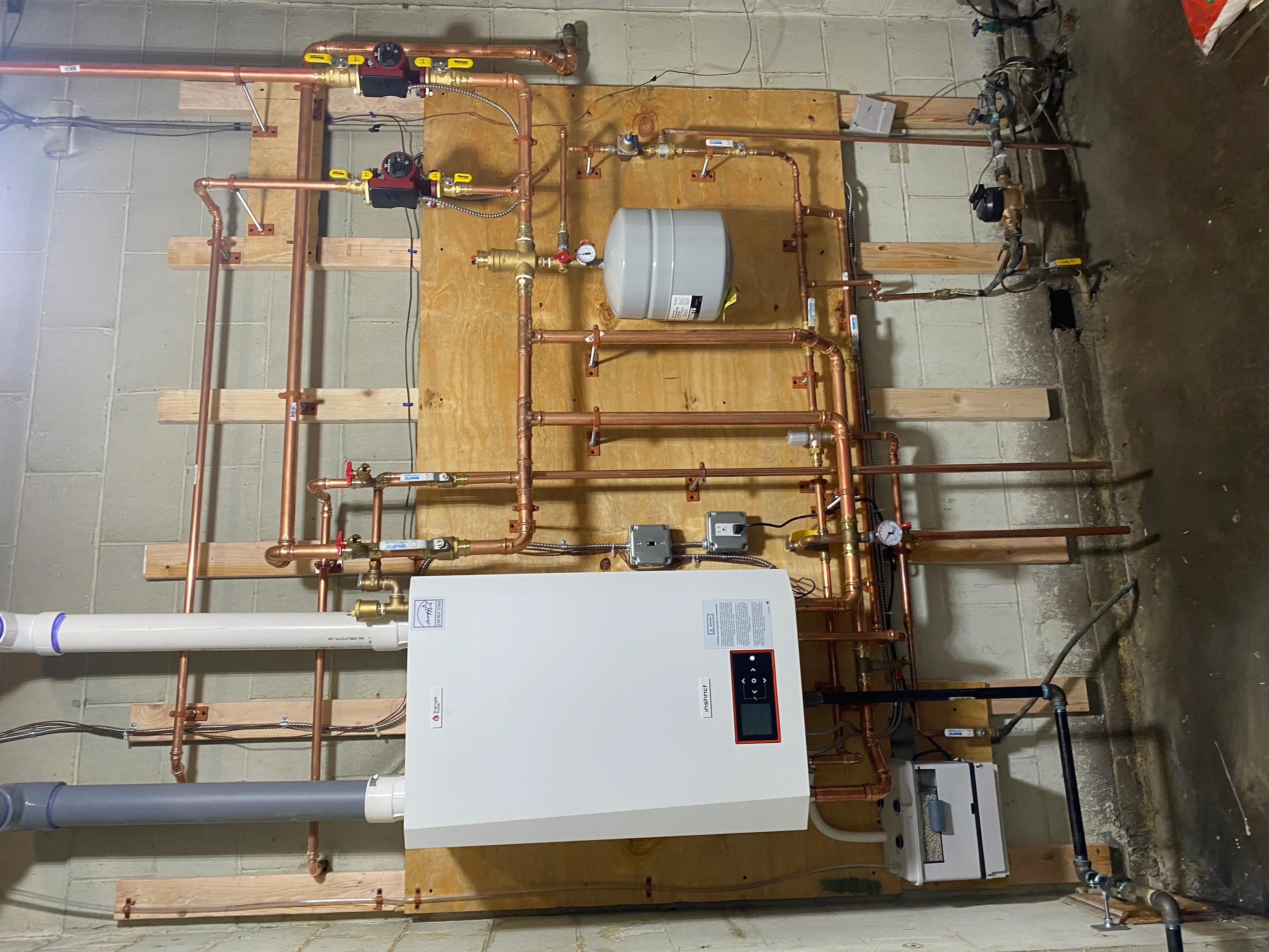 Copper radiant heating system with manifold, expansion tank, pumps, and electronic controls on plywood backing