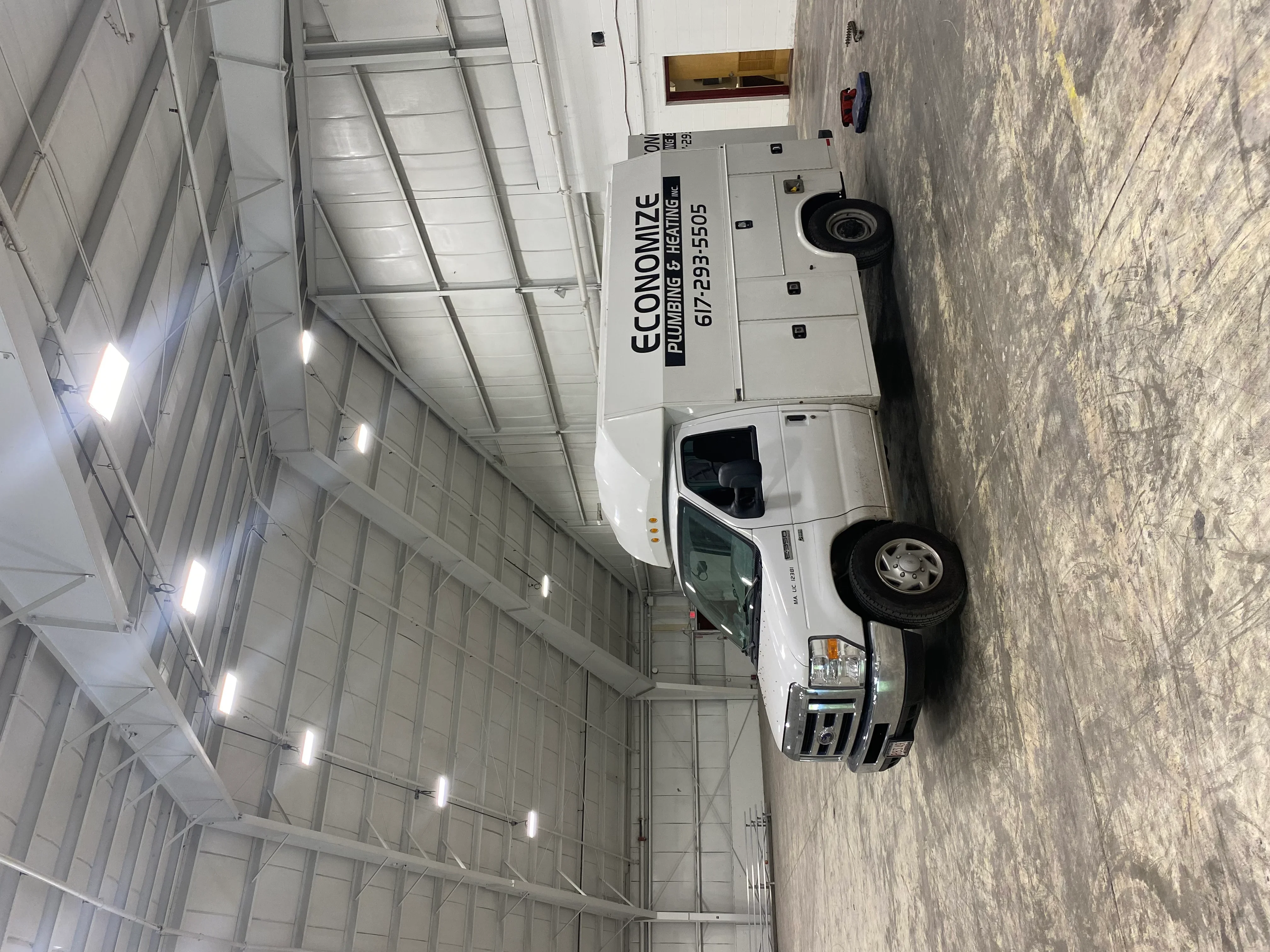 White service van with professional company branding wrap and lettering in industrial warehouse setting